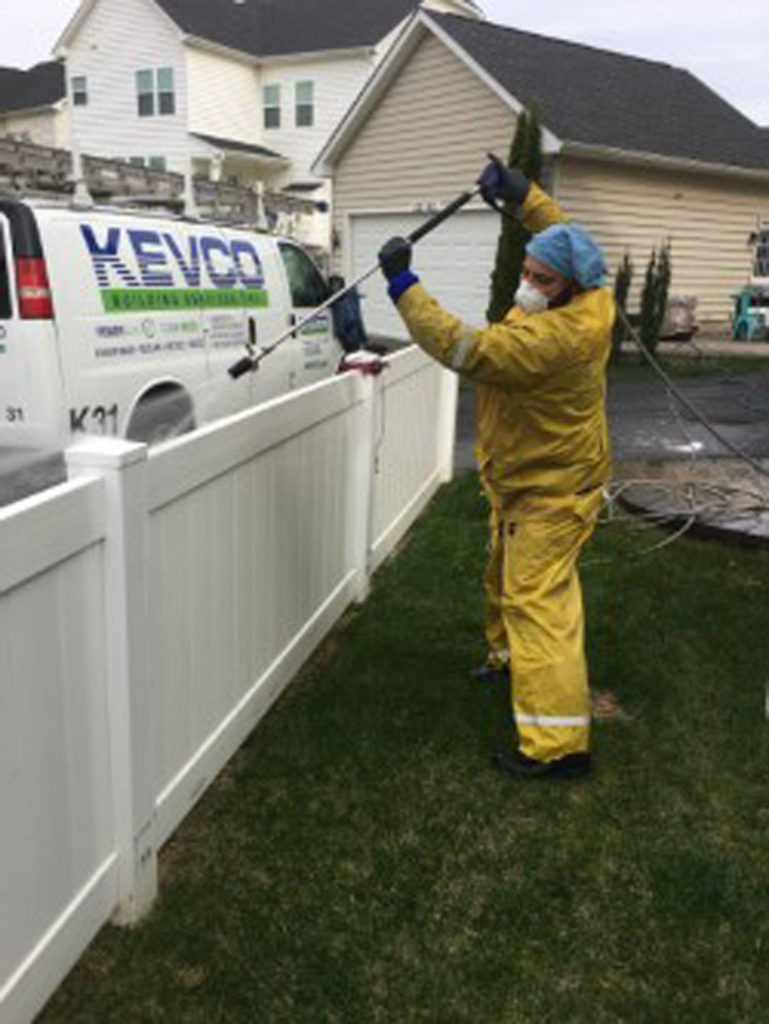 kevco employee pressure cleaning a white fence