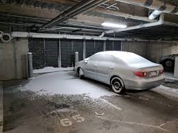 Snow covered car in a snowy parking garage.