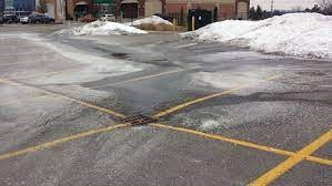 Parking lot with patches of salt, ice and snow.
